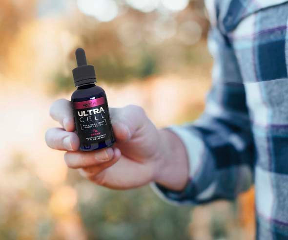 Man holding UltraCell CBD Oil, hemp oil for pain relief by Zilis and ultraZwell